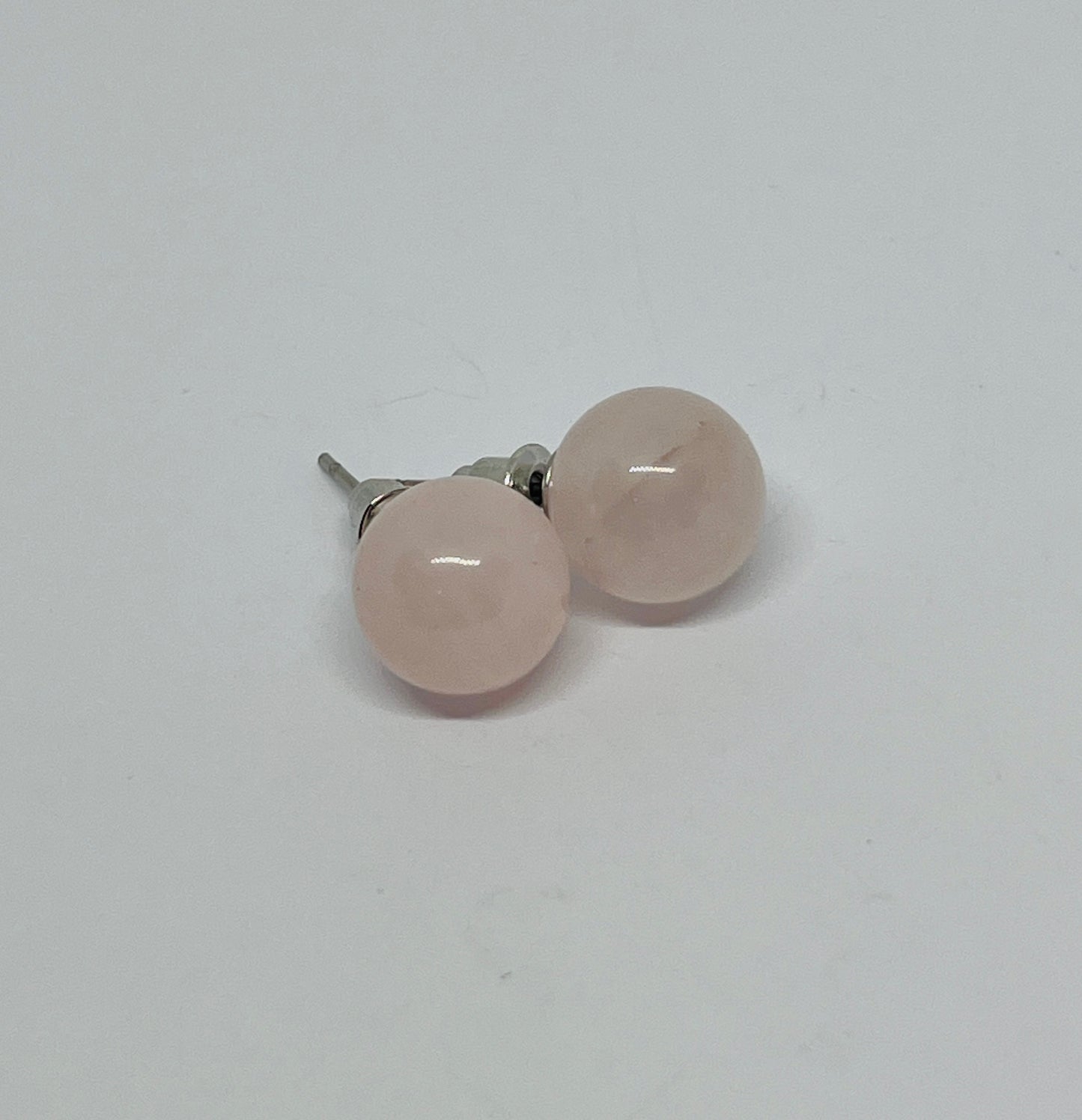 Pair of rose quartz stud earrings on a light gray background