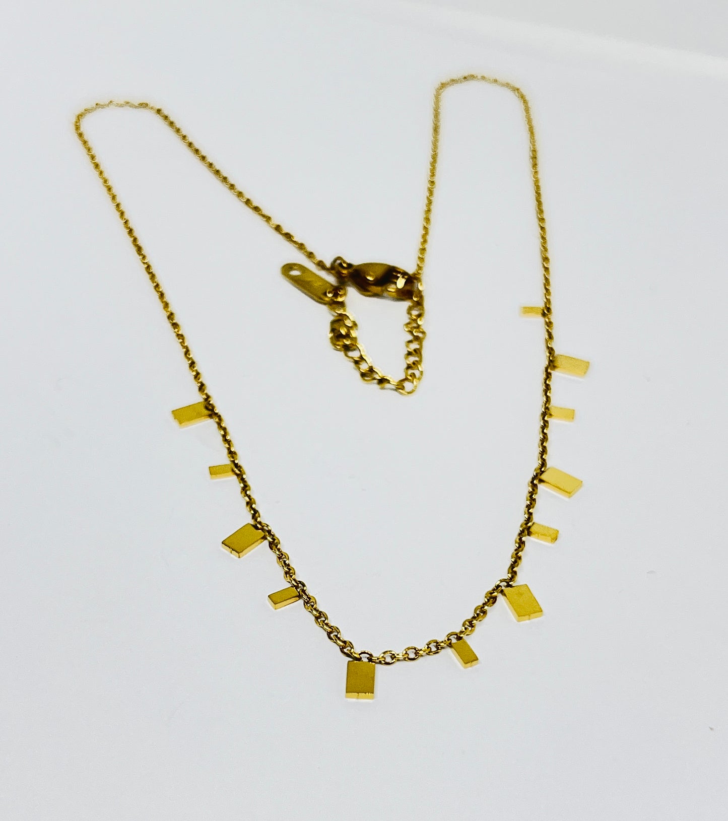 Gold necklace with rectangular pendants on a white background