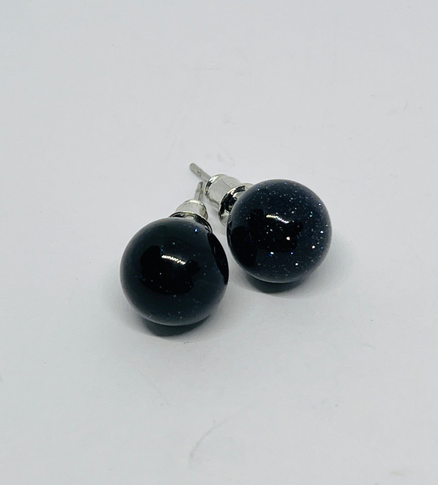 Pair of black round earrings on a light gray background