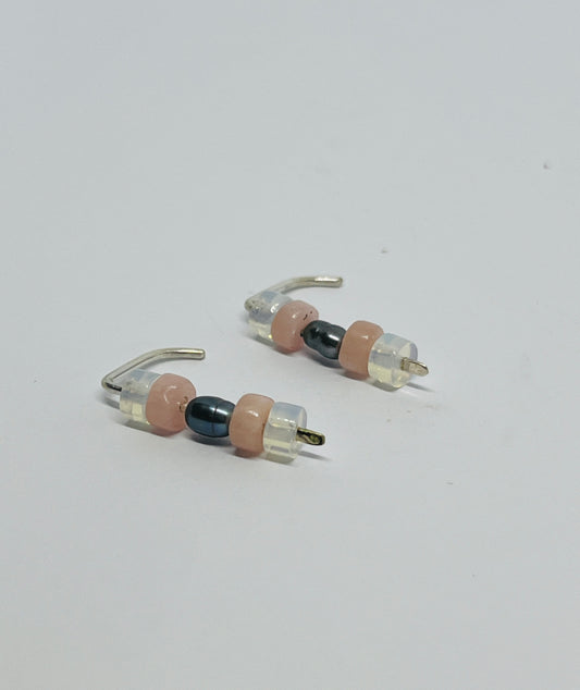 A tribute to resilience and femininity.
These exquisite earrings showcase a harmonious blend of moonstone, rose quartz, and a striking black pearl, reflecting the duality of sweetness and strength in women throughout history.