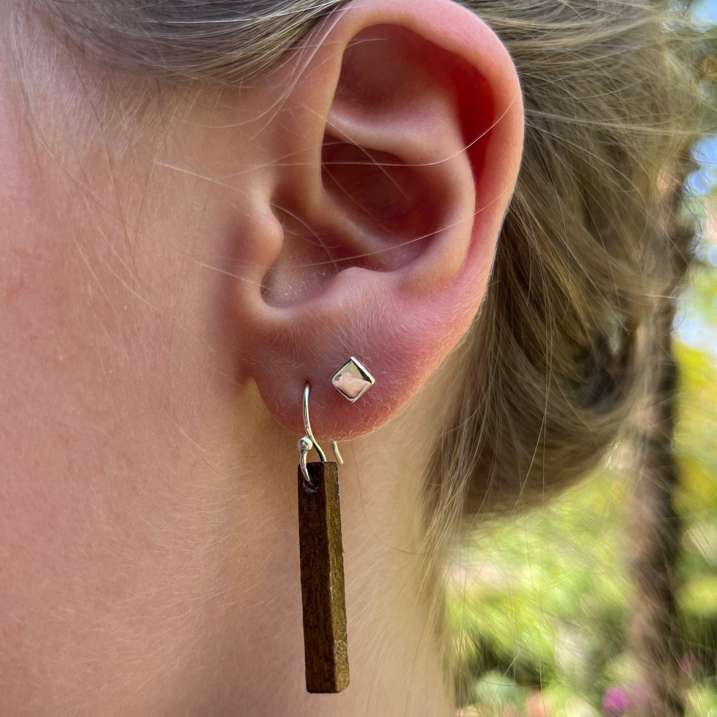 A pair of silver square stud earrings on a white background.