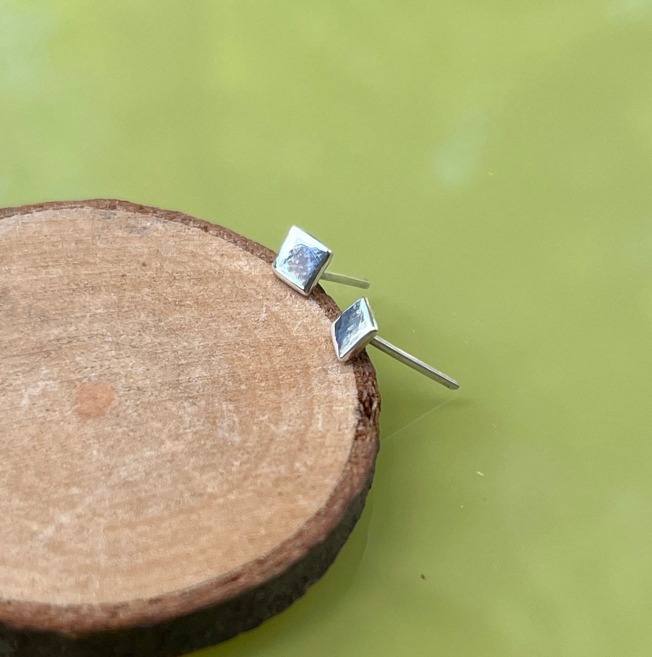 A pair of silver square stud earrings on a white background.