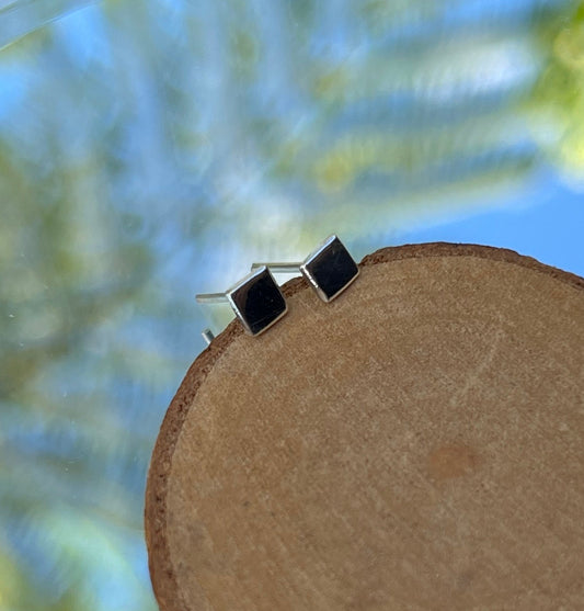 A pair of silver square stud earrings on a white background.