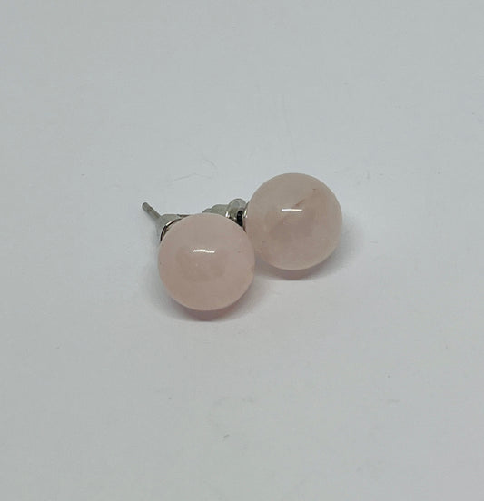Pair of rose quartz stud earrings on a light gray background