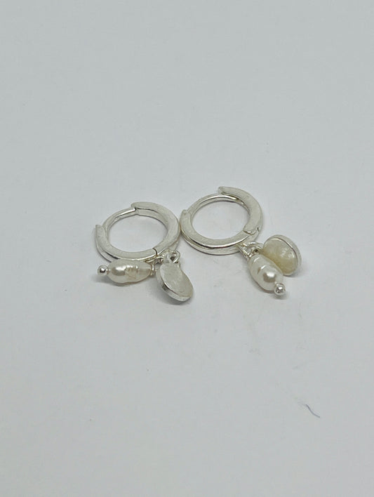 Silver hoop earrings with pearl-like charms on a light gray background