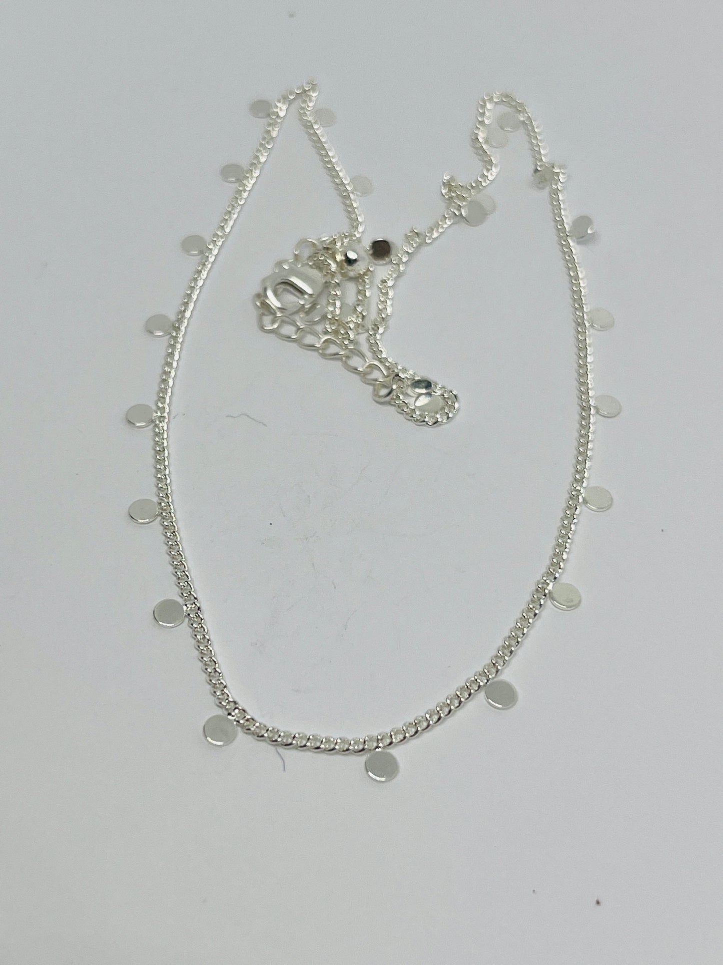 Silver necklace with circular pendants on a light gray background