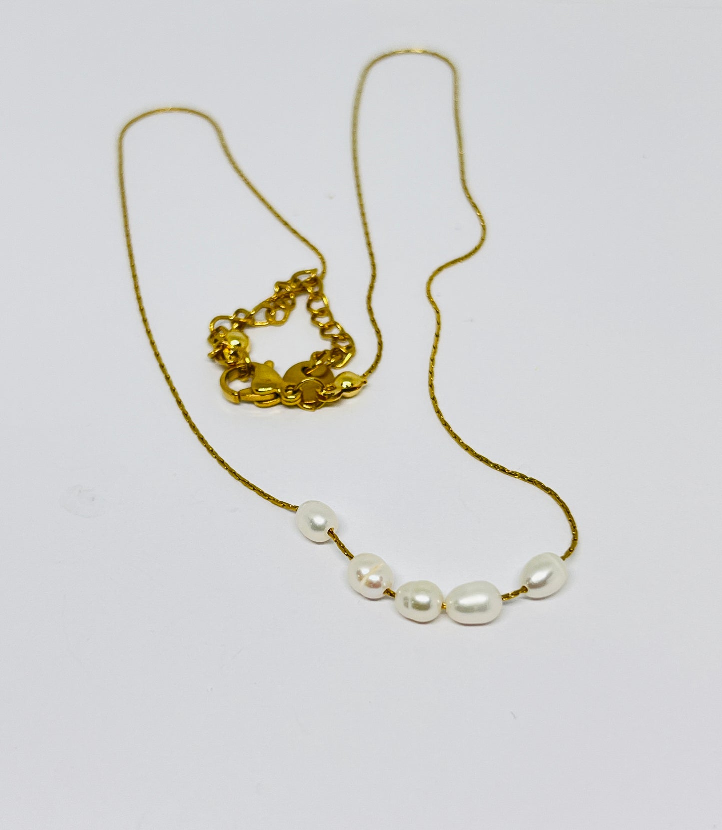 Gold necklace with pearl-like beads on a white background