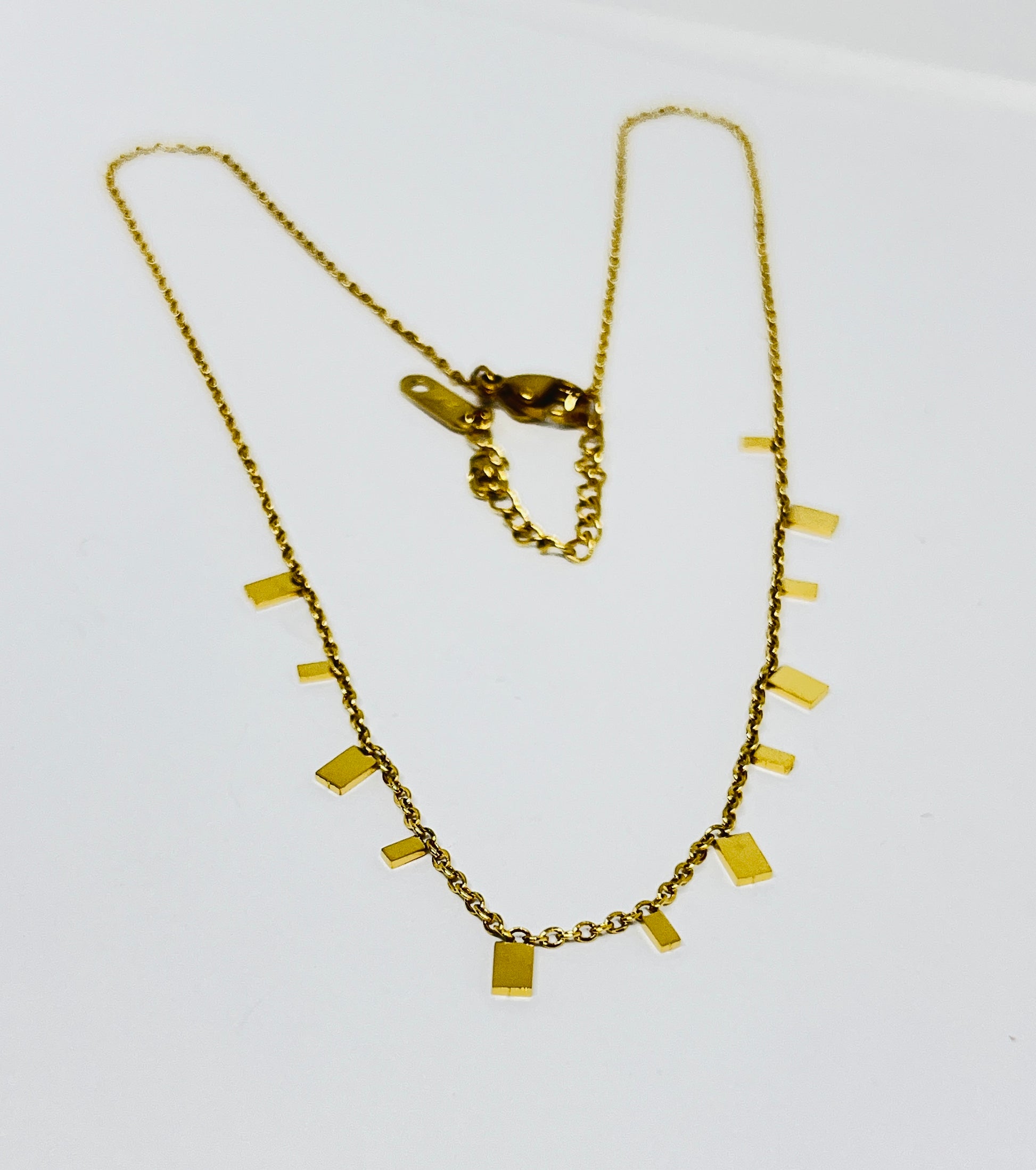 Gold necklace with rectangular pendants on a white background