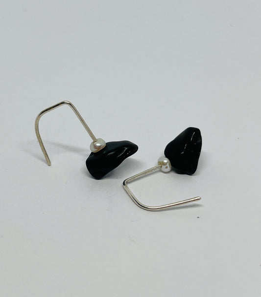 Black teardrop and small pearl earrings with silver hooks on a light gray background