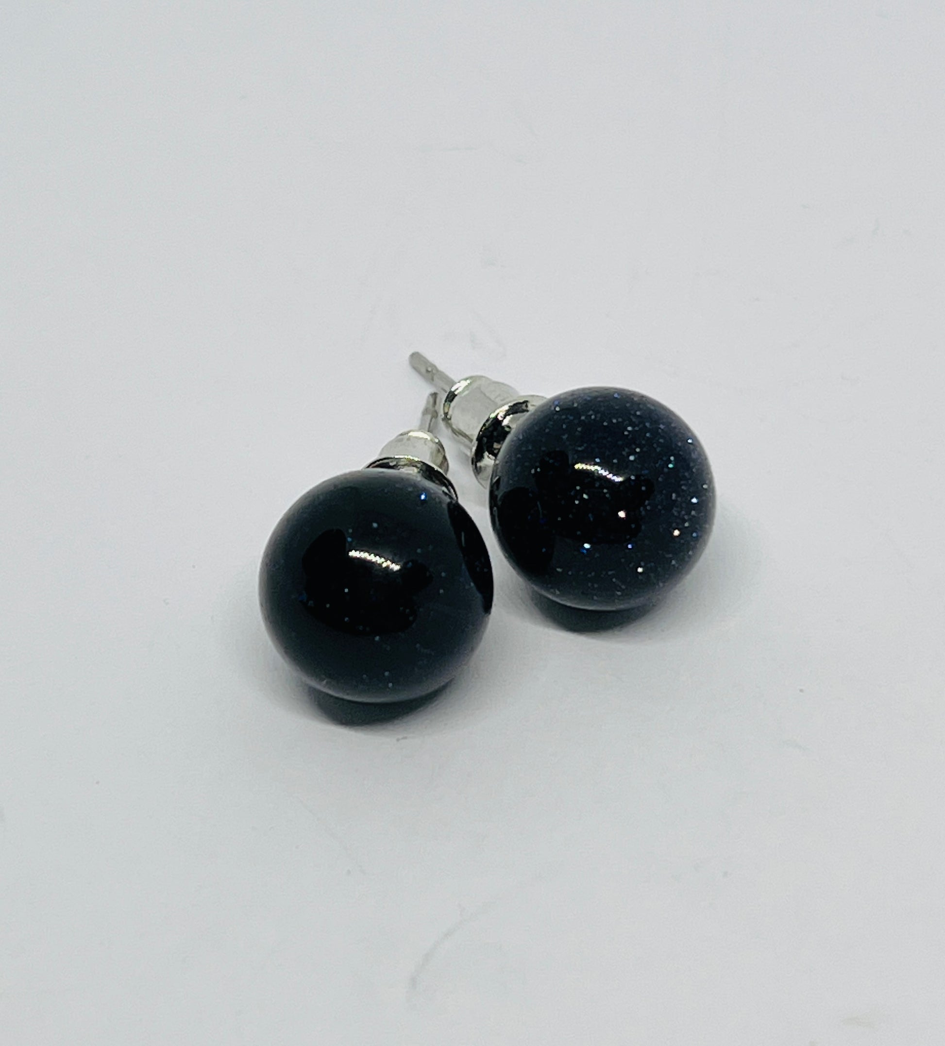 Pair of black round earrings on a light gray background