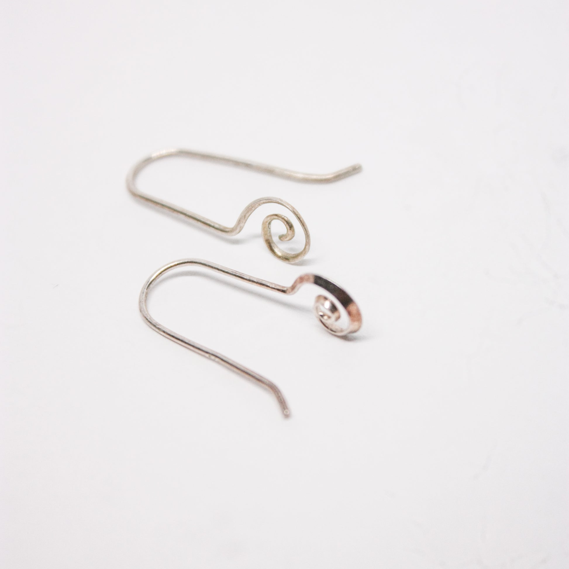 A pair of silver dangle earrings with a spiral design, displayed against a white background.