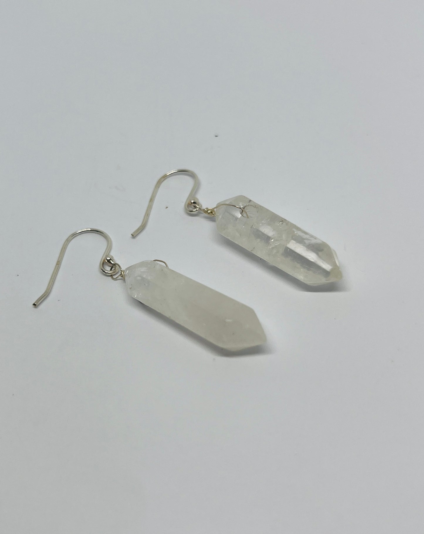 This stunning pair of dangling quartz earrings, paired with a matching pendant, embodies elegance and simplicity, creating a harmonious synergy that enhances your natural beauty. Each piece features exquisite quartz crystals, expertly wrapped in fine silver, showcasing their ethereal charm.