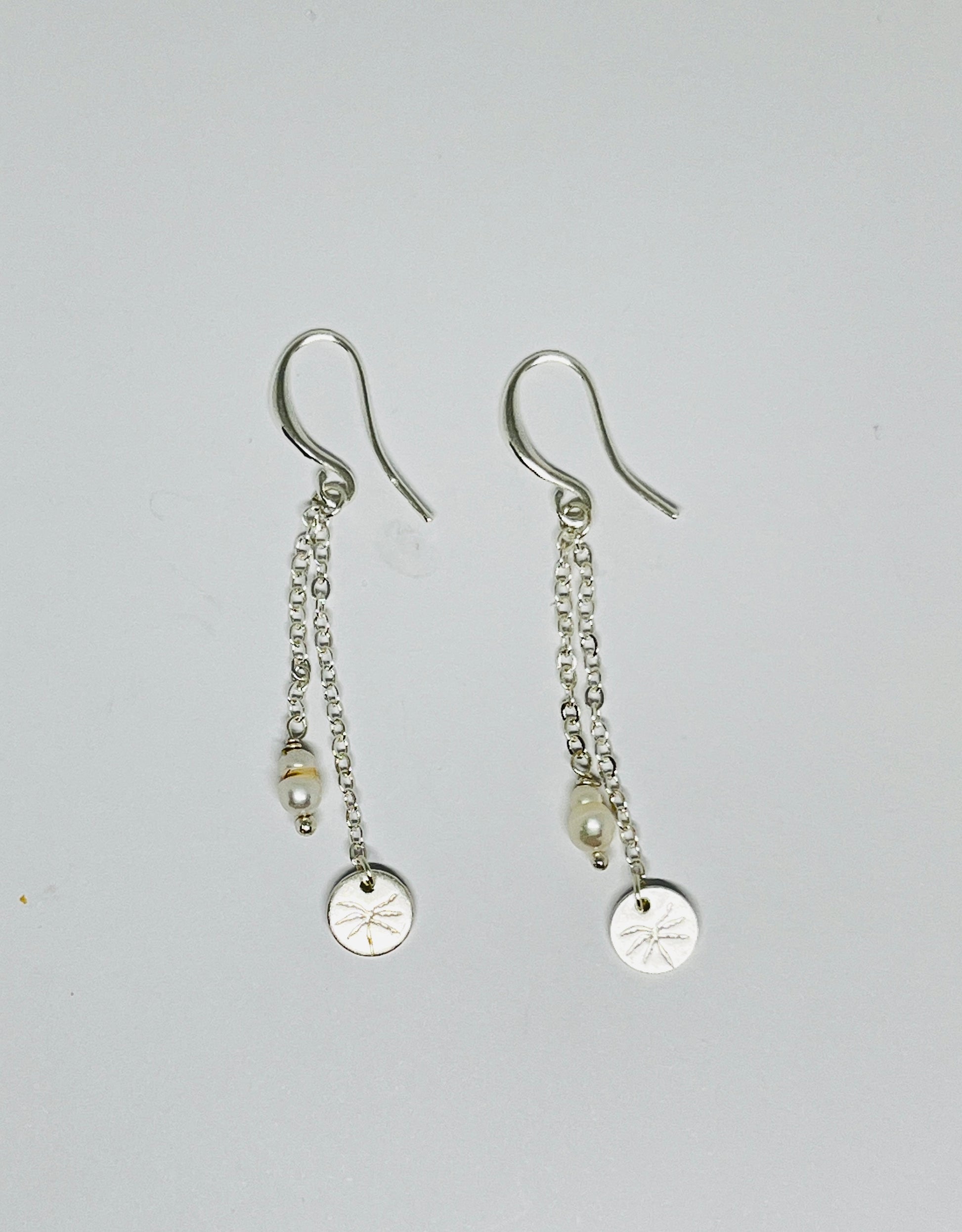 Pair of silver earrings with chain drops on a light gray background